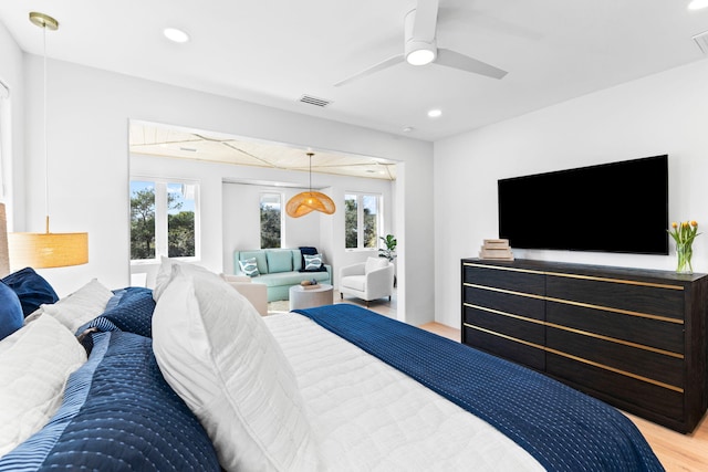 bedroom with ceiling fan, multiple windows, and light hardwood / wood-style floors