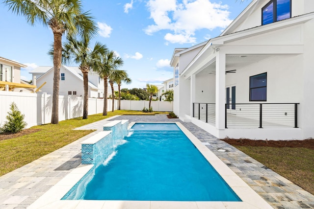 view of pool featuring pool water feature, ceiling fan, a lawn, and a patio area