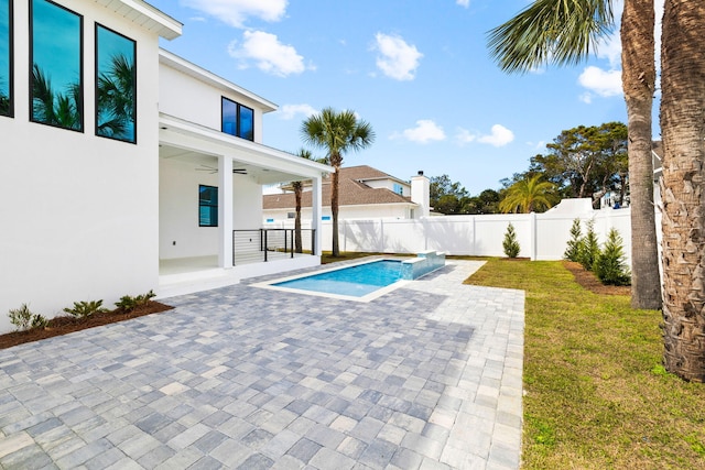 view of swimming pool with ceiling fan, a lawn, and a patio