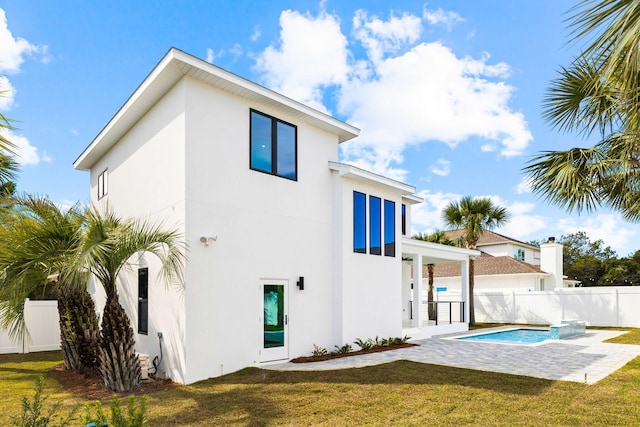 back of property with a patio area, a fenced in pool, and a lawn