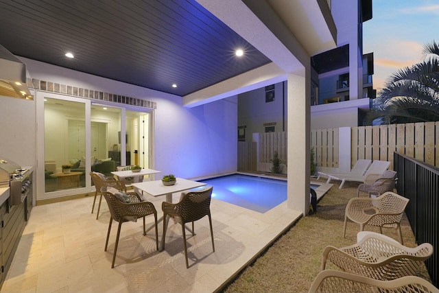 pool at dusk with a patio area and grilling area