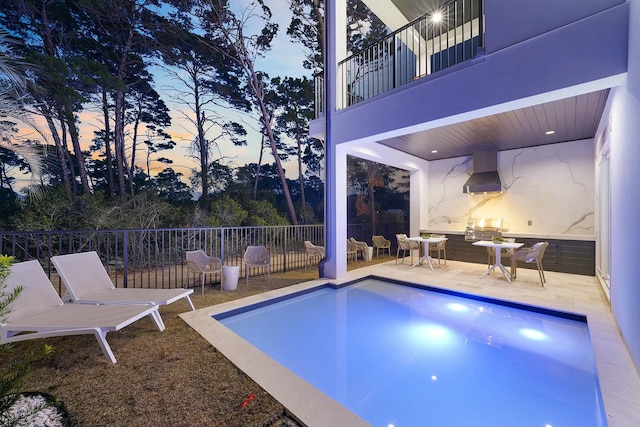 pool at dusk featuring a patio area and grilling area