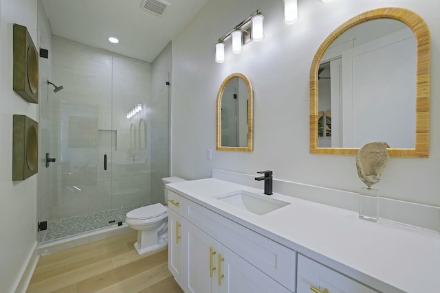 bathroom with hardwood / wood-style floors, toilet, walk in shower, and vanity