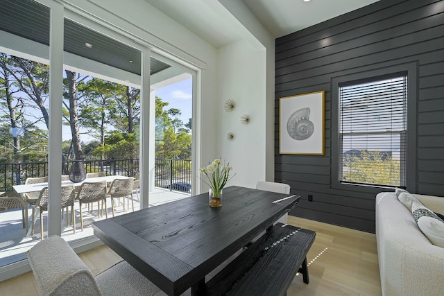 dining space with light wood-type flooring and wooden walls