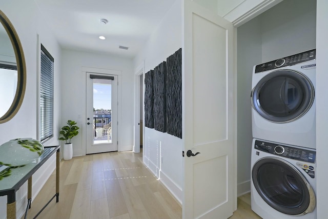 laundry room featuring light wood-type flooring and stacked washer and clothes dryer