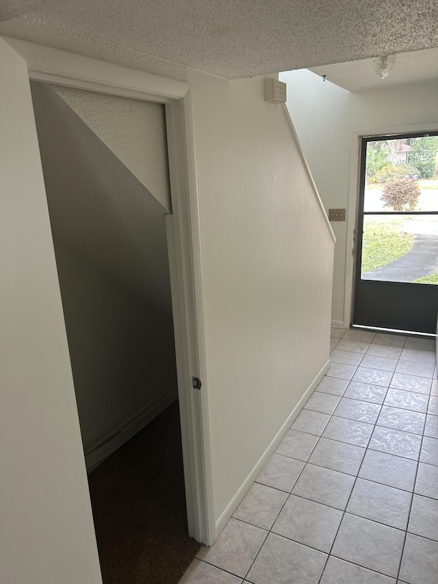 hall featuring light tile patterned floors and a textured ceiling