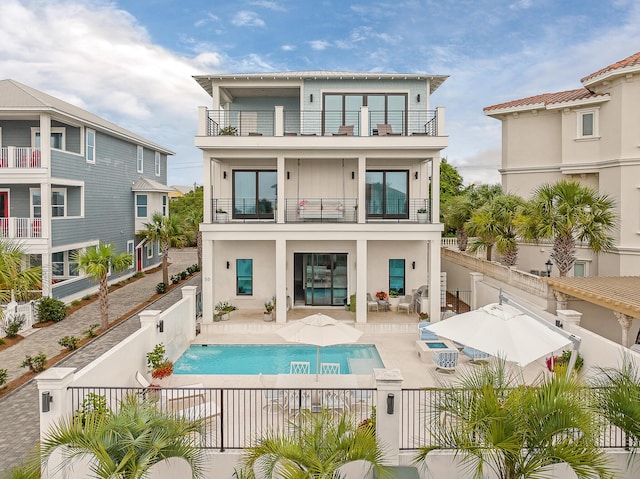 back of house with a patio, a balcony, and a fenced in pool