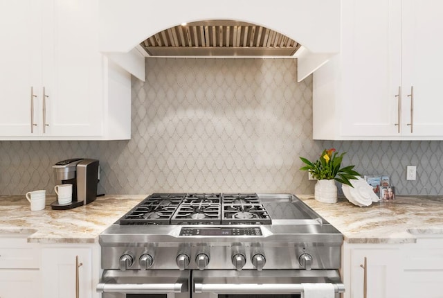 kitchen with light stone countertops, white cabinetry, tasteful backsplash, and range with two ovens