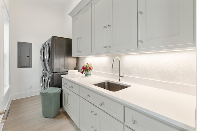 kitchen featuring stacked washer / drying machine, backsplash, electric panel, white cabinets, and sink