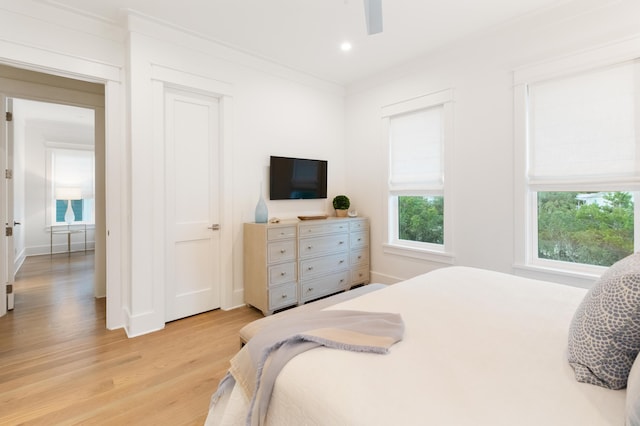 bedroom featuring ceiling fan, crown molding, and light hardwood / wood-style flooring