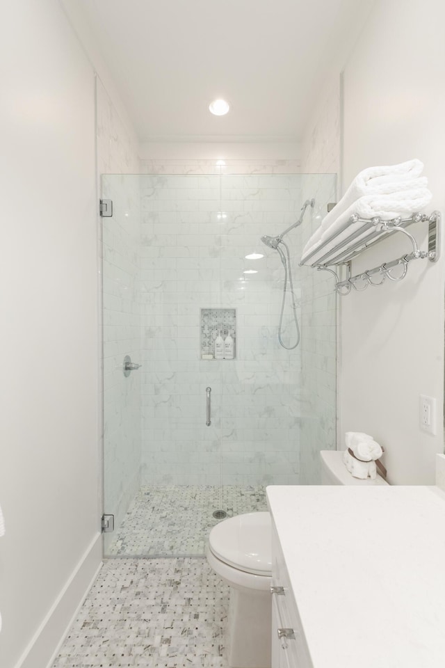 bathroom featuring toilet, vanity, and a shower with door