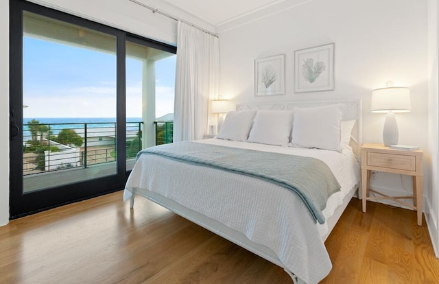 bedroom featuring hardwood / wood-style floors, ornamental molding, and a water view