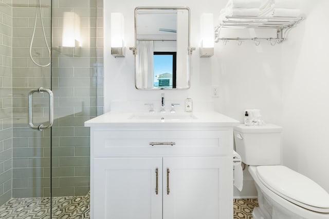 bathroom with toilet, vanity, and a shower with door