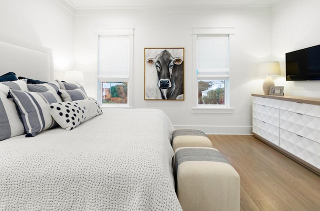 bedroom with crown molding and light hardwood / wood-style floors