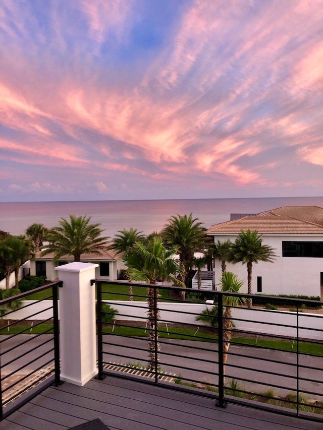 deck at dusk featuring a water view