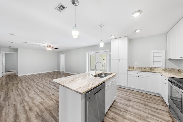 kitchen featuring sink, appliances with stainless steel finishes, white cabinetry, light stone counters, and an island with sink