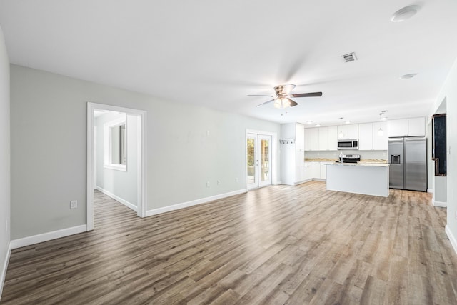 unfurnished living room featuring ceiling fan, light hardwood / wood-style floors, and french doors