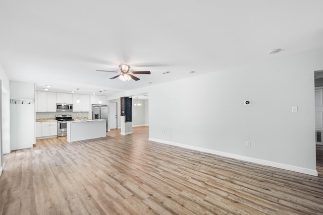 unfurnished living room with sink, light hardwood / wood-style floors, and ceiling fan