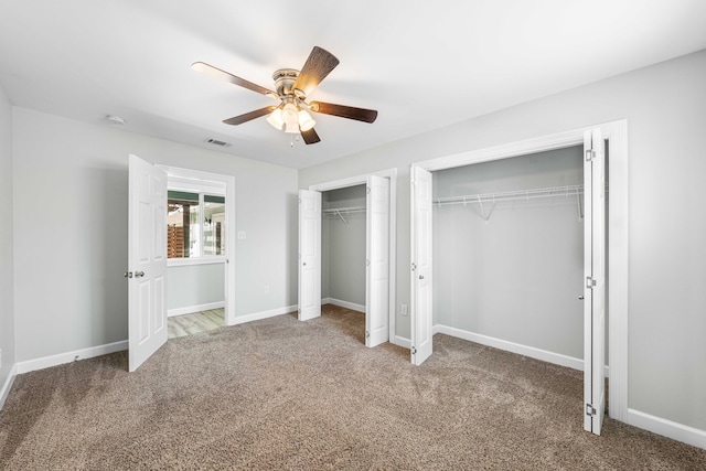 unfurnished bedroom featuring ceiling fan, carpet flooring, and two closets