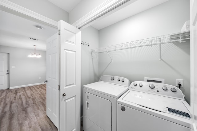 clothes washing area featuring separate washer and dryer, an inviting chandelier, and light hardwood / wood-style flooring