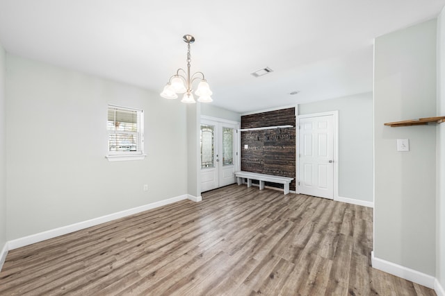 unfurnished living room featuring a chandelier and light hardwood / wood-style floors