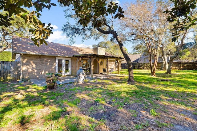 rear view of property featuring french doors, a patio, and a lawn