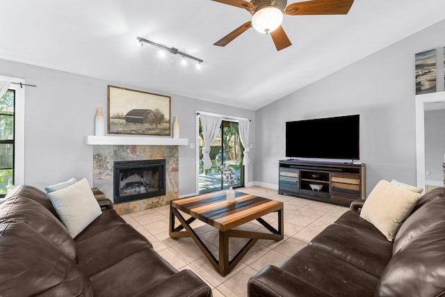 living room with vaulted ceiling, a tile fireplace, a healthy amount of sunlight, and light tile patterned floors