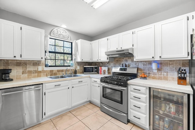 kitchen with stainless steel appliances, wine cooler, sink, tasteful backsplash, and white cabinets