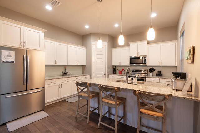 kitchen with hanging light fixtures, light stone counters, stainless steel appliances, and white cabinetry