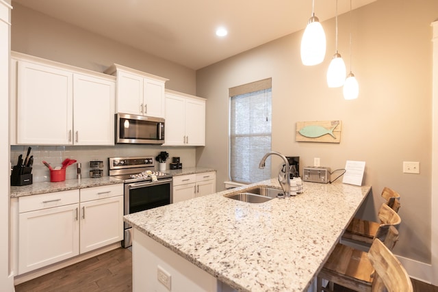 kitchen with decorative light fixtures, sink, light stone countertops, appliances with stainless steel finishes, and white cabinets