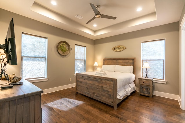 bedroom featuring ceiling fan, dark wood-type flooring, and a raised ceiling