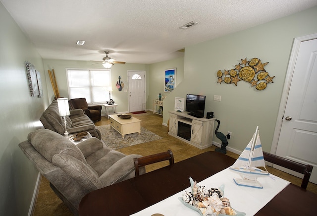 living room featuring ceiling fan, a fireplace, and a textured ceiling