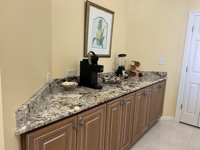 bar with light tile patterned flooring and light stone counters