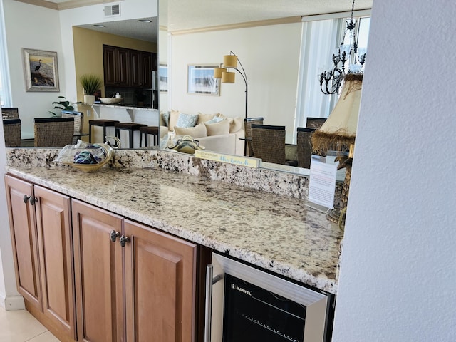 kitchen with wine cooler, pendant lighting, light stone countertops, and light tile patterned flooring