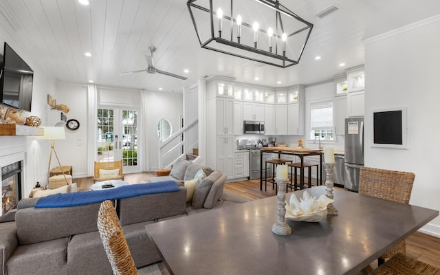 dining area with a healthy amount of sunlight, a large fireplace, wood ceiling, and crown molding