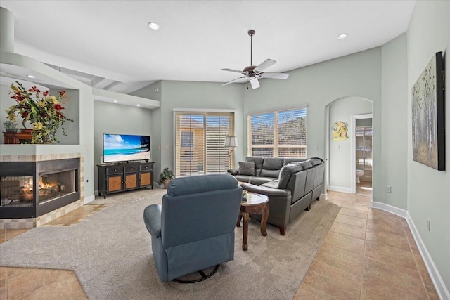 living room with a multi sided fireplace, vaulted ceiling, ceiling fan, and light tile patterned flooring