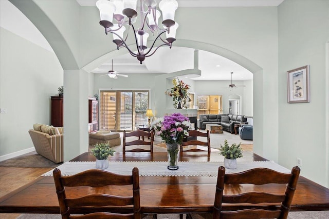 dining room featuring ceiling fan with notable chandelier and a high ceiling