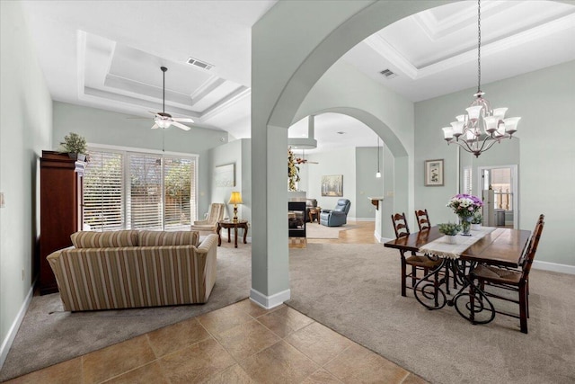 carpeted dining area with ceiling fan, a tray ceiling, and ornamental molding