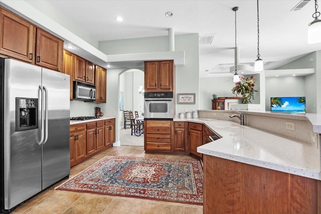 kitchen with kitchen peninsula, pendant lighting, sink, light stone countertops, and stainless steel appliances