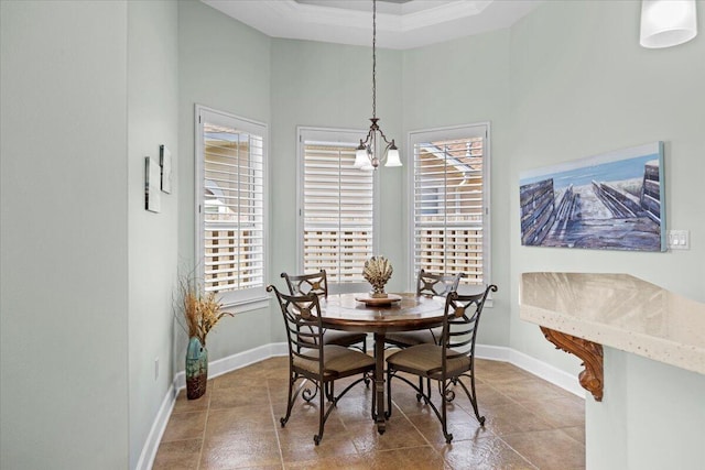 dining area with a high ceiling, a raised ceiling, crown molding, and an inviting chandelier