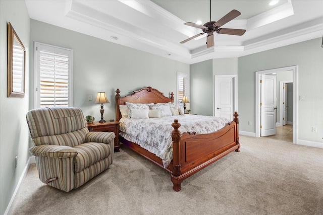 carpeted bedroom with ceiling fan, a raised ceiling, and ornamental molding