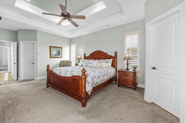 carpeted bedroom with ceiling fan, multiple windows, a tray ceiling, and crown molding