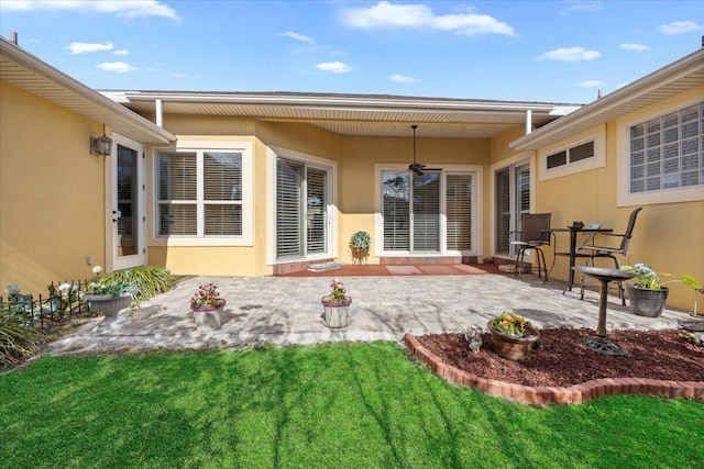 back of property with ceiling fan, a lawn, and a patio