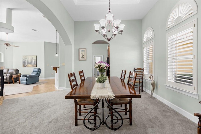 dining area with ceiling fan with notable chandelier and light colored carpet