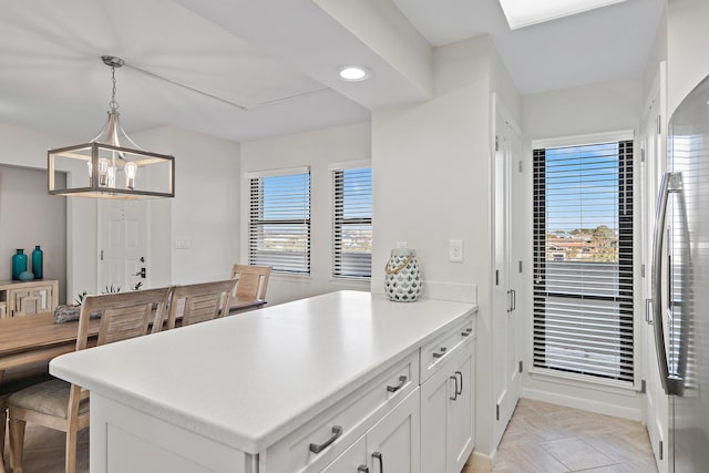 kitchen with a wealth of natural light, decorative light fixtures, kitchen peninsula, and white cabinets