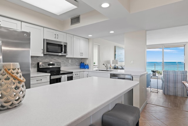 kitchen featuring white cabinetry, sink, stainless steel appliances, a water view, and tile patterned floors