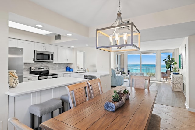 tiled dining room with a water view, sink, and a notable chandelier