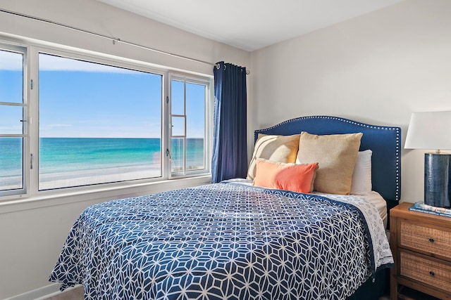 bedroom featuring multiple windows, a beach view, and a water view