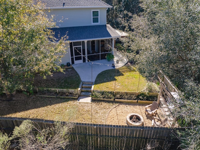 back of house with a fire pit, a sunroom, a patio, and a lawn