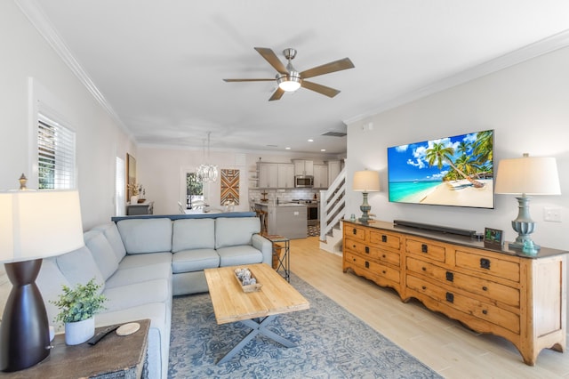 living room with light wood-type flooring, ceiling fan, and crown molding